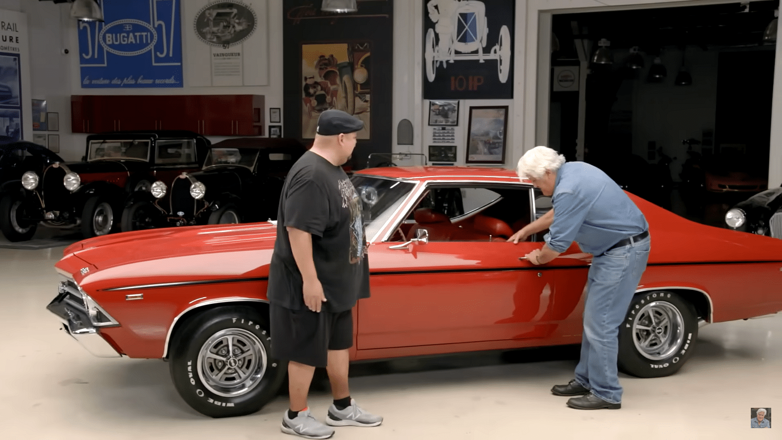 Gabriel Iglesias and Jay Leno taking a look at a red 1969 Chevy Chevelle SS390